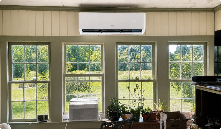 Air conditioning unit mounted on a wall with large windows showing greenery outside